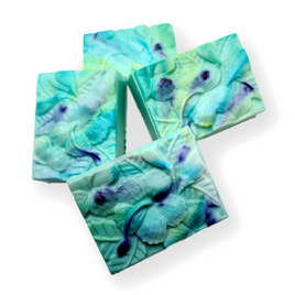 three bars of teal and blue tie dye colored soap bars styled with hbiscus flower patterns
