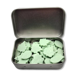 an open tin of small green soaps shaped like leaves